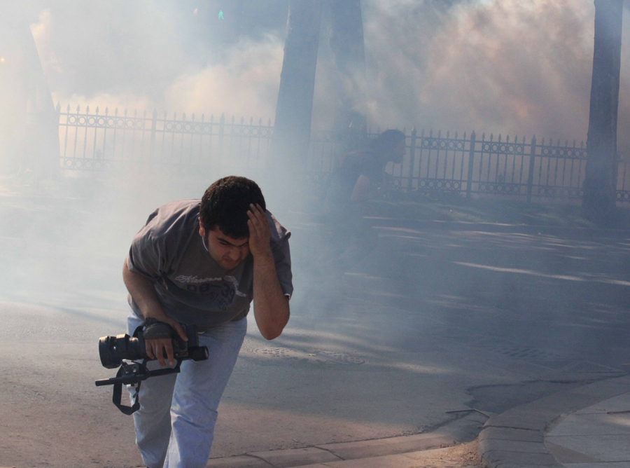 Diha muhabirinin çıplak kolları atılan gaz bombalarından korunmasına yetmiyor; fakat daha önemlisi, gaz bombalarının gücü elden kamerayı bıraktırmaya yetmiyor. Kim daha güçlü?