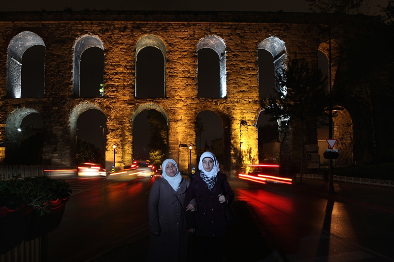 Warda (39) ve Shahd(18) Alasal, Şam. Fatih’in giriş kapısı olarak nitelenen Haşim İşcan geçidinde fotoğraflandılar. Anne Alasal kira ücretlerin artması ve Suriyelilerin ucuz işgücü olarak değerlendirilmesinden yakınıyor. İç savaş nedeniyle İngiltere’ye yerleşen eşinin kendilerini oraya almasını bekliyorlar. Kızı Shahd ise İngiltere’ye gidecek olmalarına ve İngilizce bilmemesine rağmen bir buçuk yıldır Türkçe eğitimine devam ediyor. 